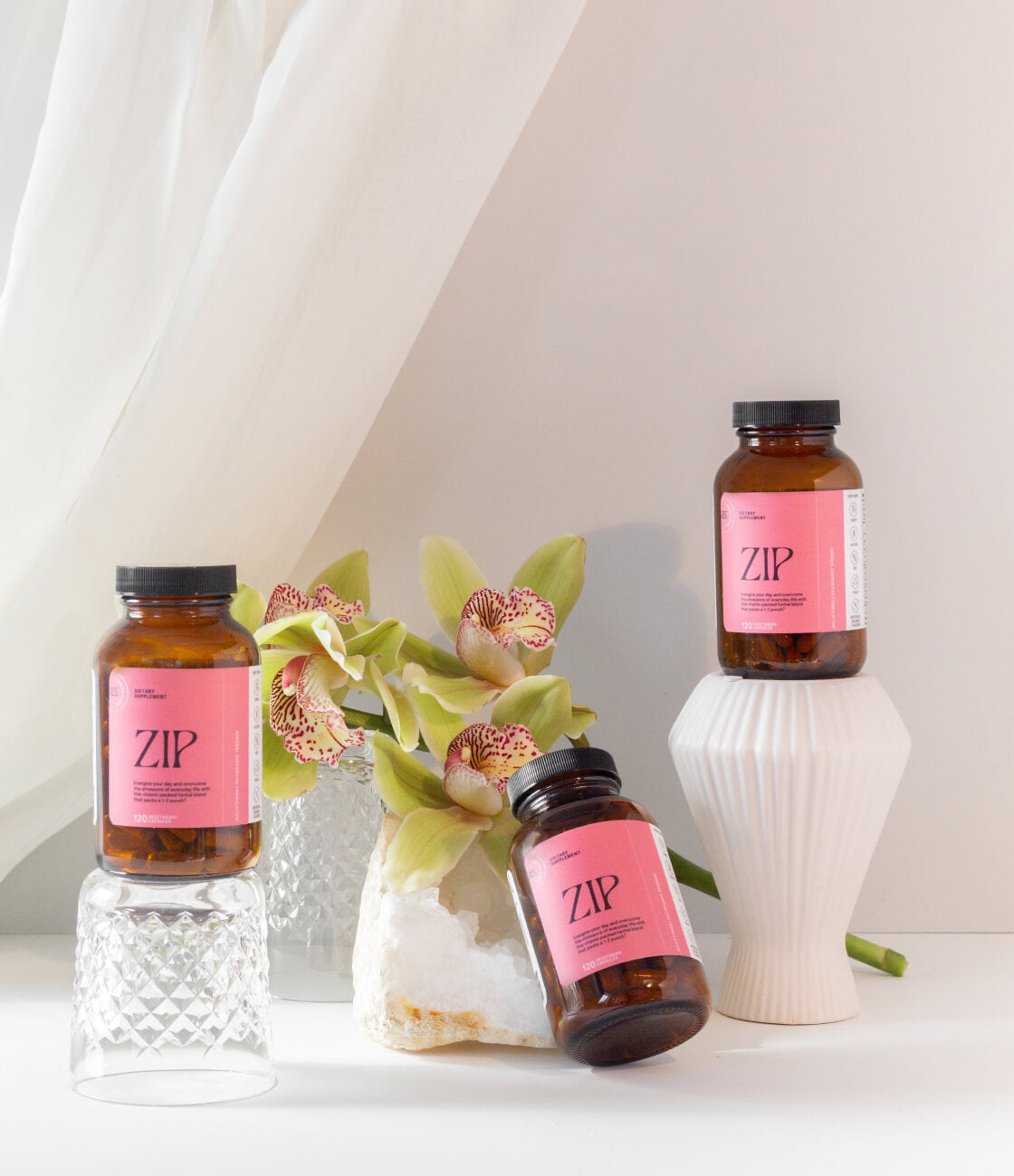 Zip is beautiful enough to sit on your counter so you remember to take them everyday and beat stress, fatigue and get back to being your energetic self. [AD: 3 bottle of Zip on a luxurious backdrop at different height with a beautiful flower in the background]